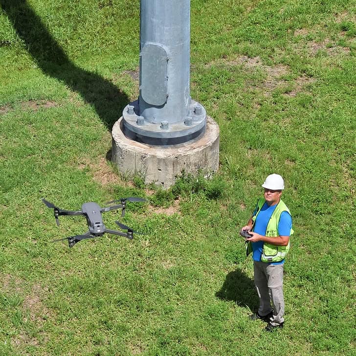 img-equipment-02 Drone inspecting utility pole with a technician on a grassy area.
