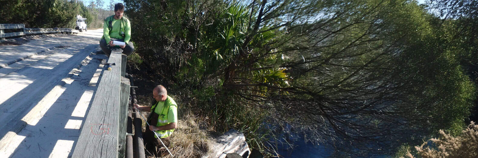 Stormwater management professionals inspecting a drainage system along a rural road.